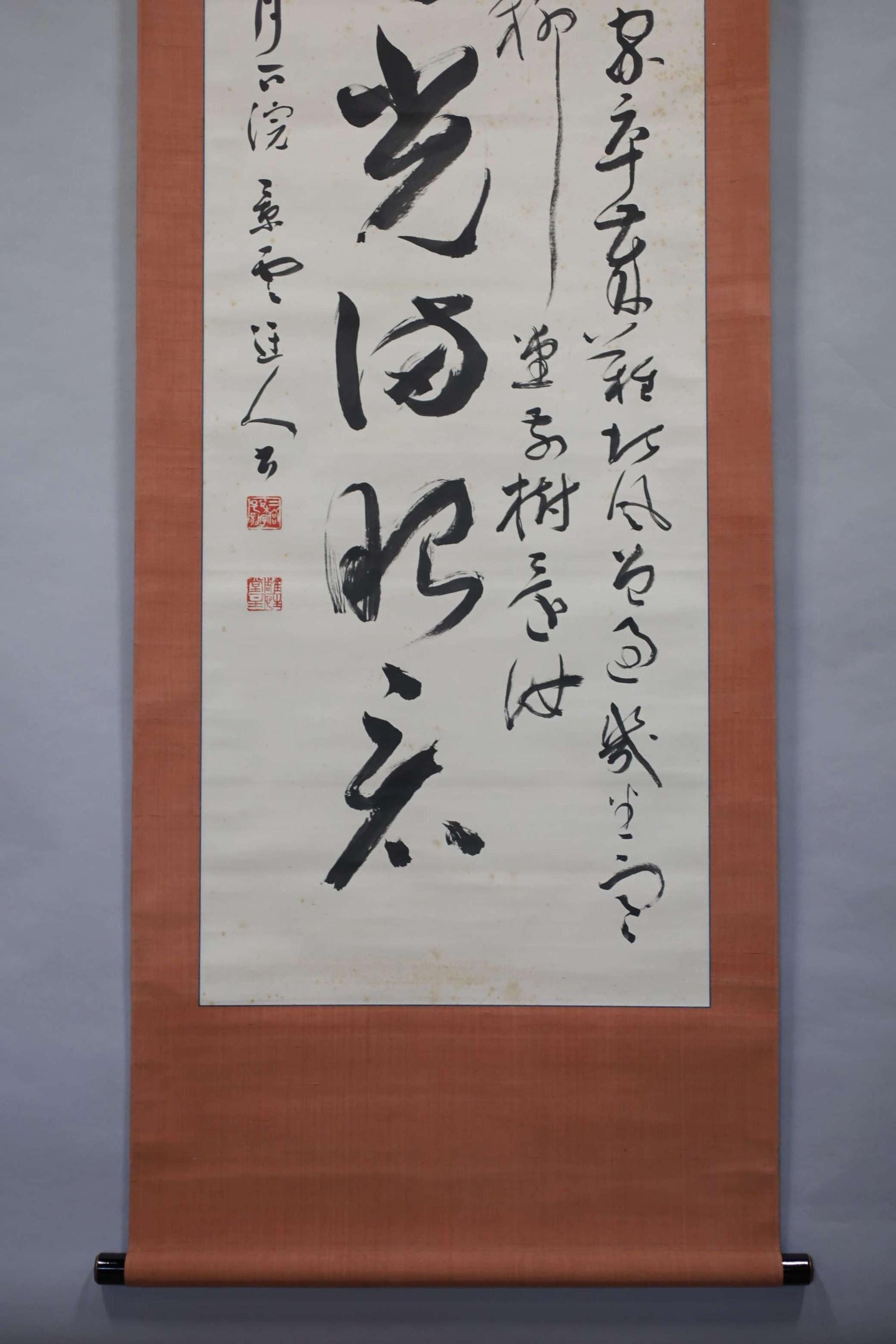 a large scroll with Chinese characters on it. The scroll is hanging on a wall, and the text appears to be in a foreign language. The scroll is quite large, occupying a significant portion of the wall space. The image does not contain any other objects or text, and the focus is solely on the scroll and its characters.