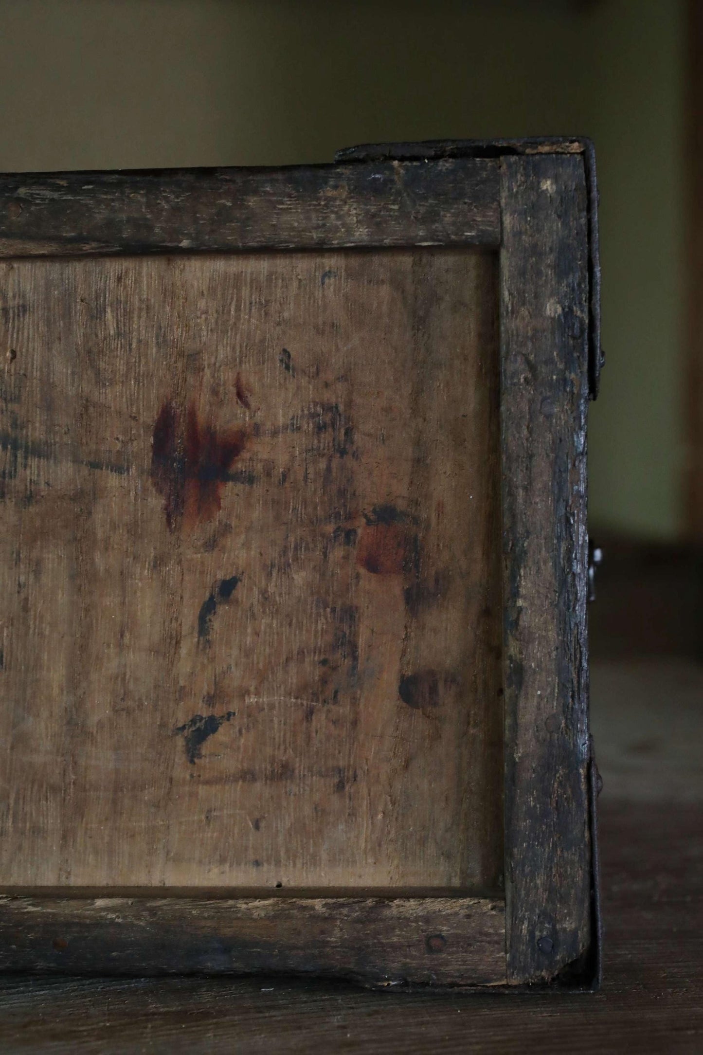 a close-up view of a weathered, wooden surface with visible stains and marks, suggesting it has been exposed to the elements for an extended period of time.