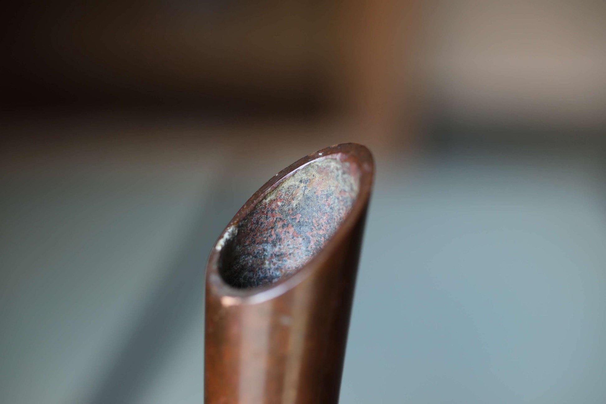 A close-up view of a rusted metal pipe or tube, with a reddish-brown color and visible rust or corrosion on its surface.
