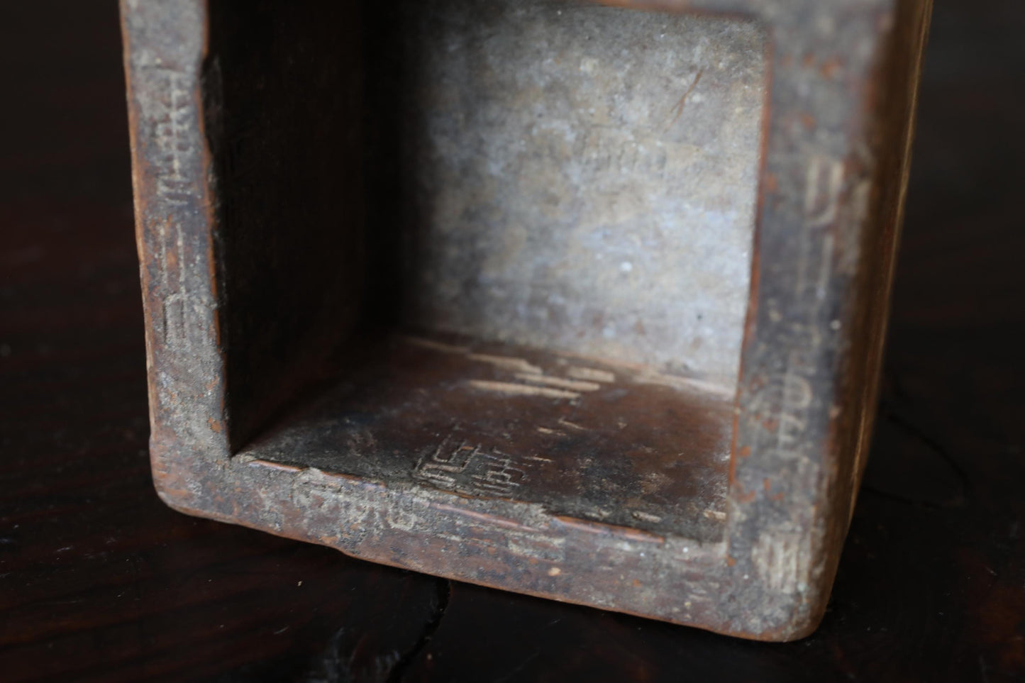 a close-up view of a rusted metal object, possibly a piece of furniture or a decorative item, with a textured surface and some markings or engravings.