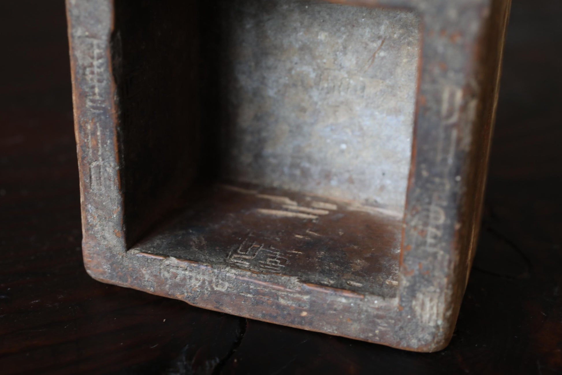 a close-up view of a rusted metal object, possibly a piece of furniture or a decorative item, with a textured surface and some markings or engravings.
