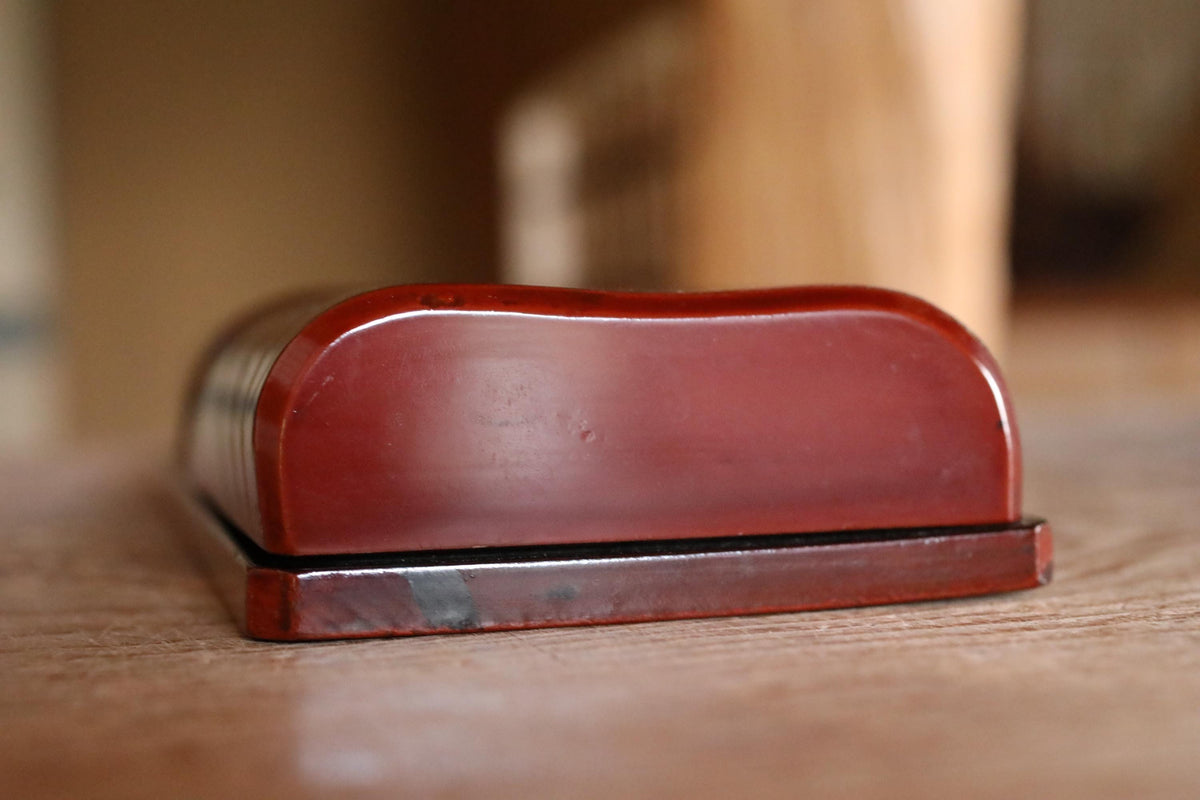 A red wooden object, possibly a box or container, is sitting on a wooden surface.