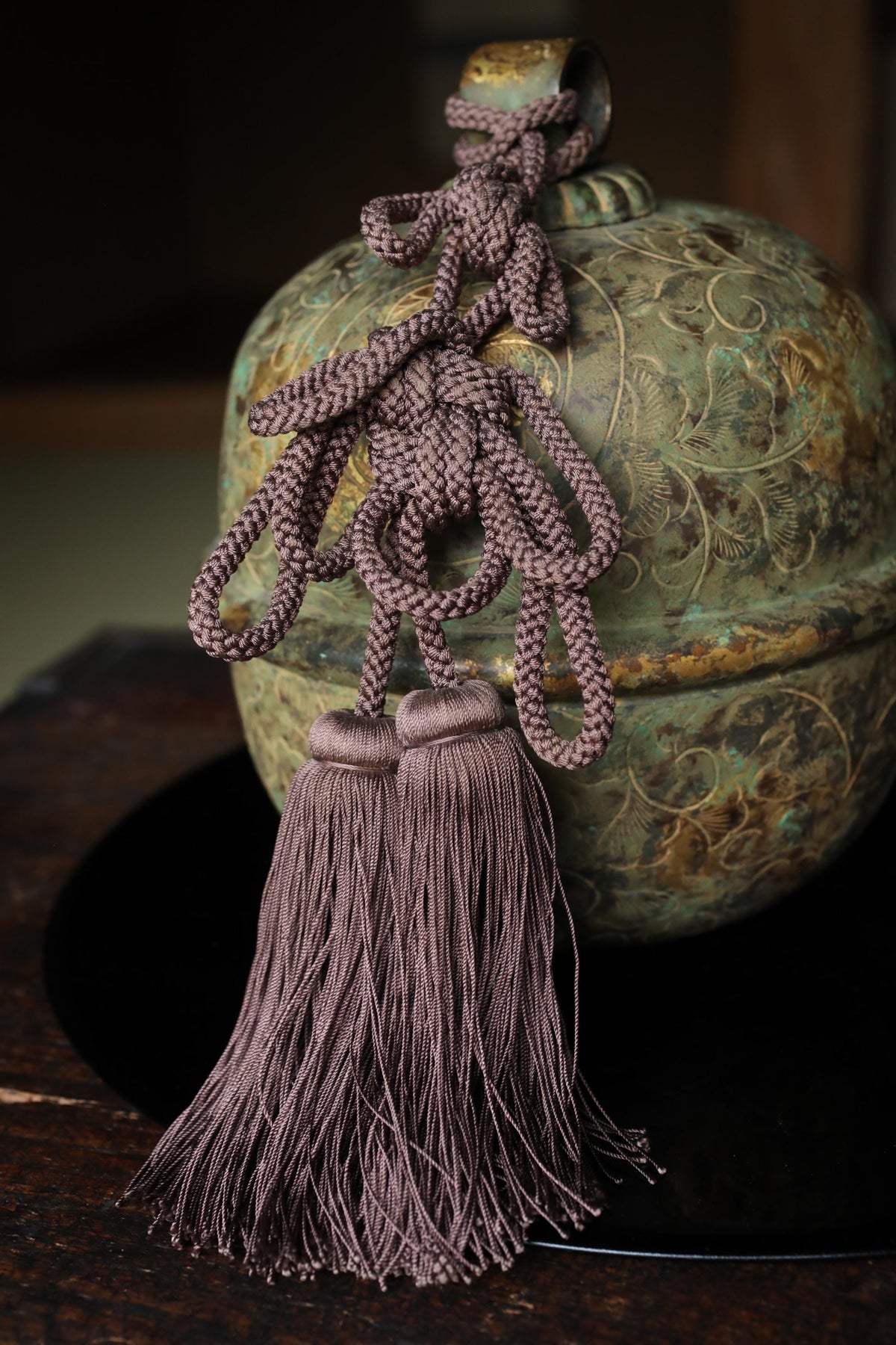 a decorative ceramic bell with a tassel hanging from it.