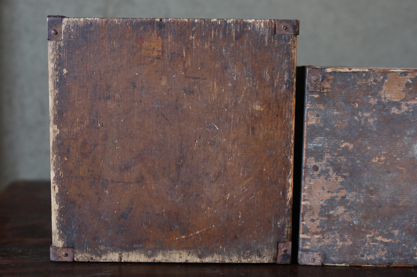 two old, weathered wooden boxes with visible signs of wear and tear, including peeling paint and visible cracks.