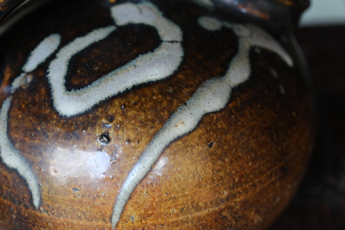 A close-up view of a brown and white ceramic vase with a distinctive design.