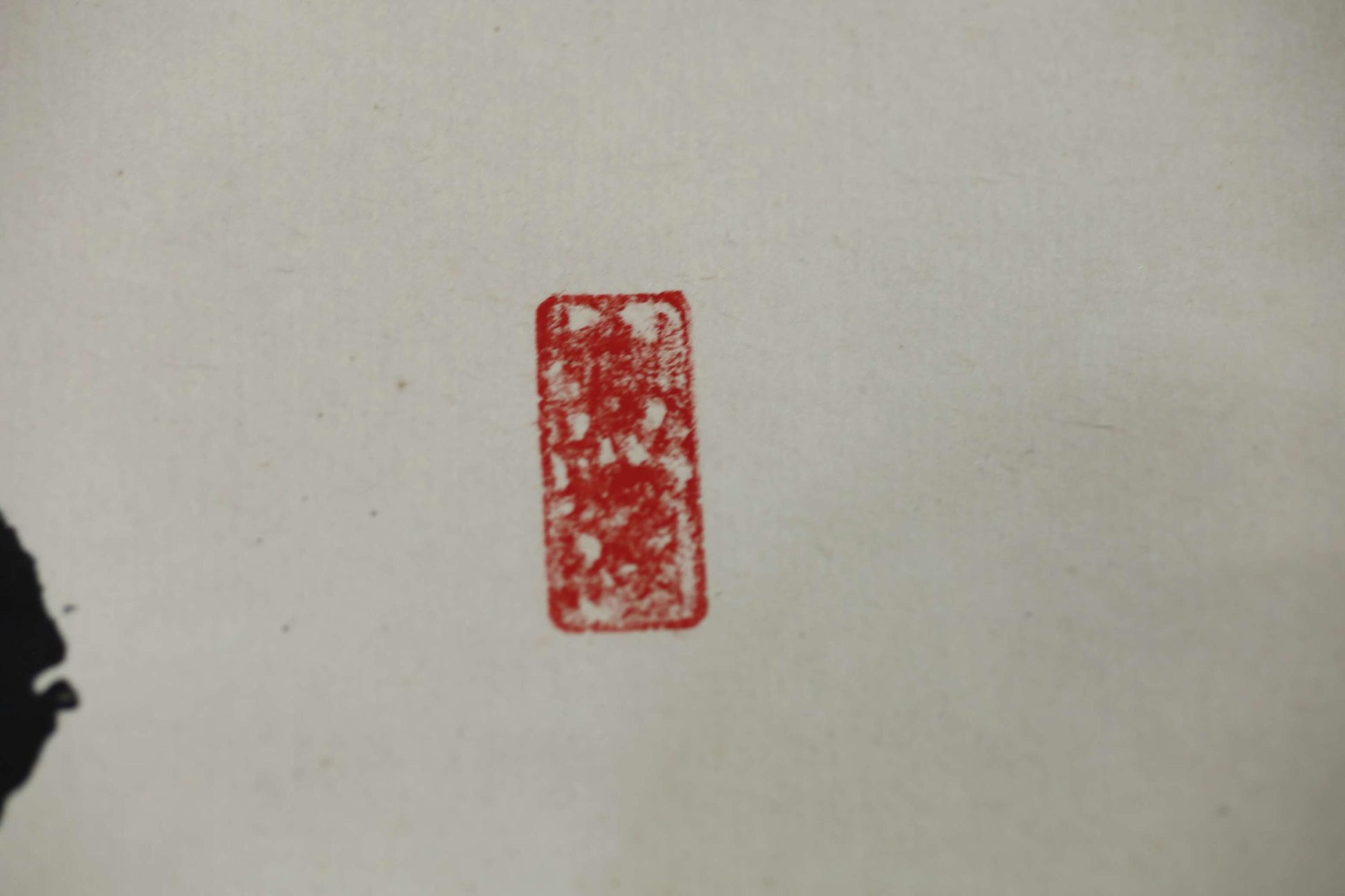 A single red stamp or seal with a decorative design on a plain white background.