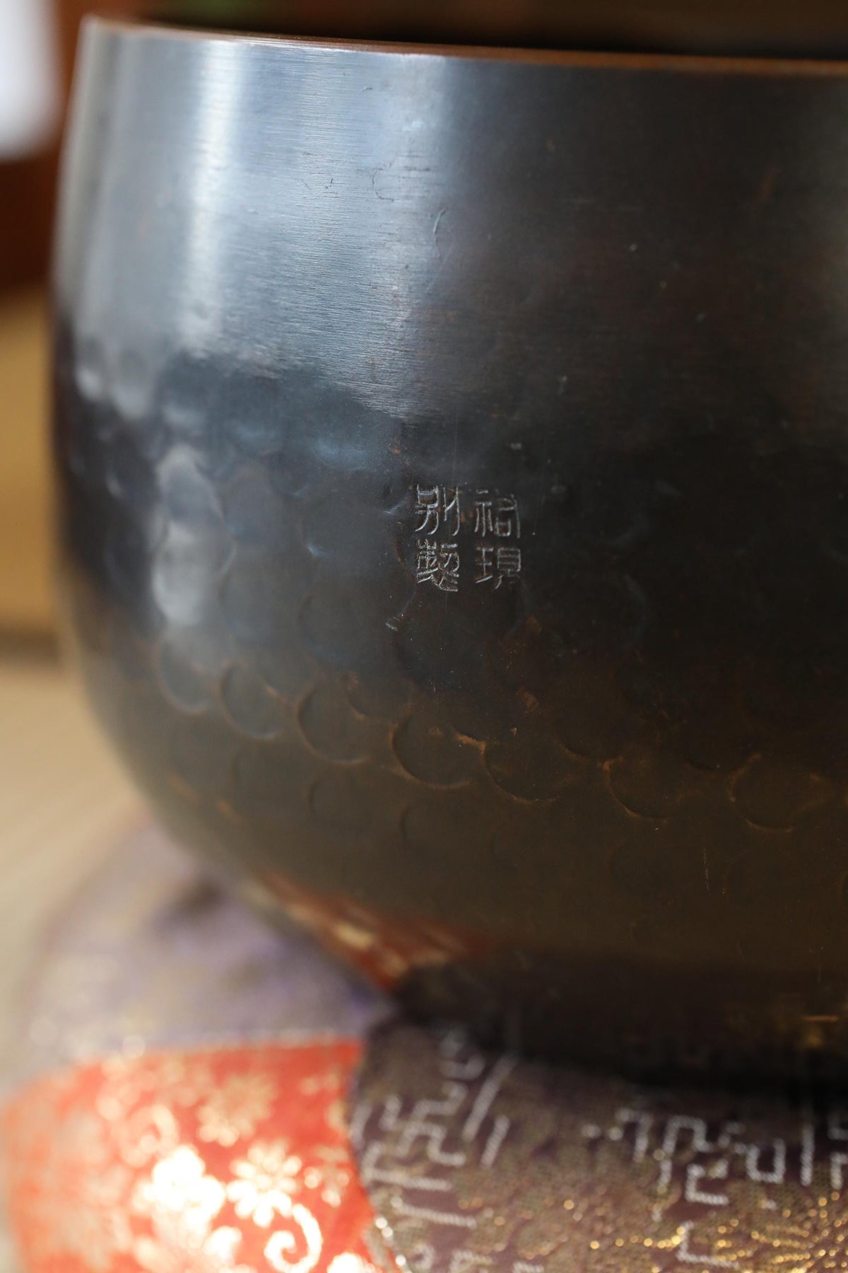 A close-up image of a dark metal bowl with a Chinese character engraved on it.