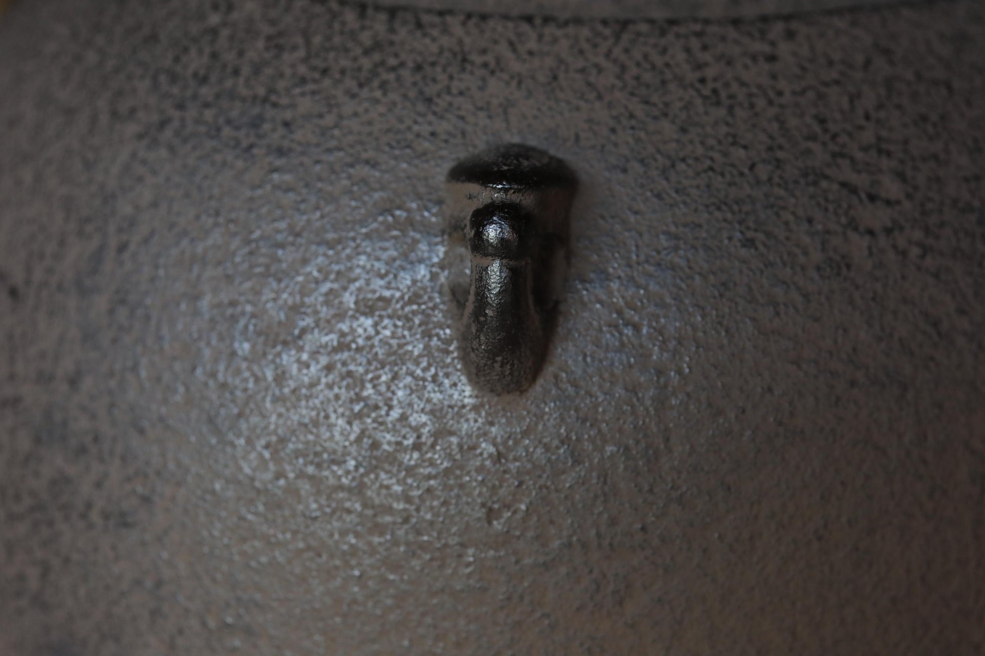 a close-up view of a metal object, possibly a bolt or nut, attached to a textured surface.