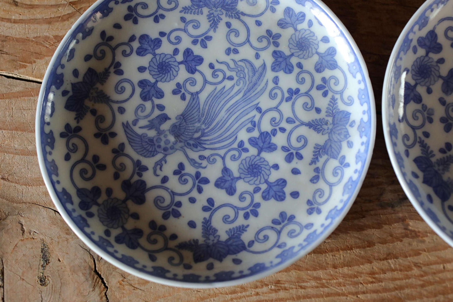 A close-up image of a decorative blue and white plate with a floral pattern, resting on a wooden surface.