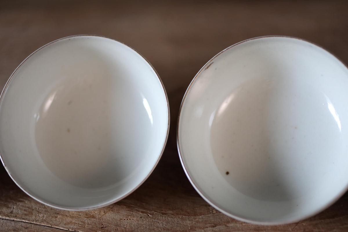 Two white bowls placed side by side on a wooden surface.