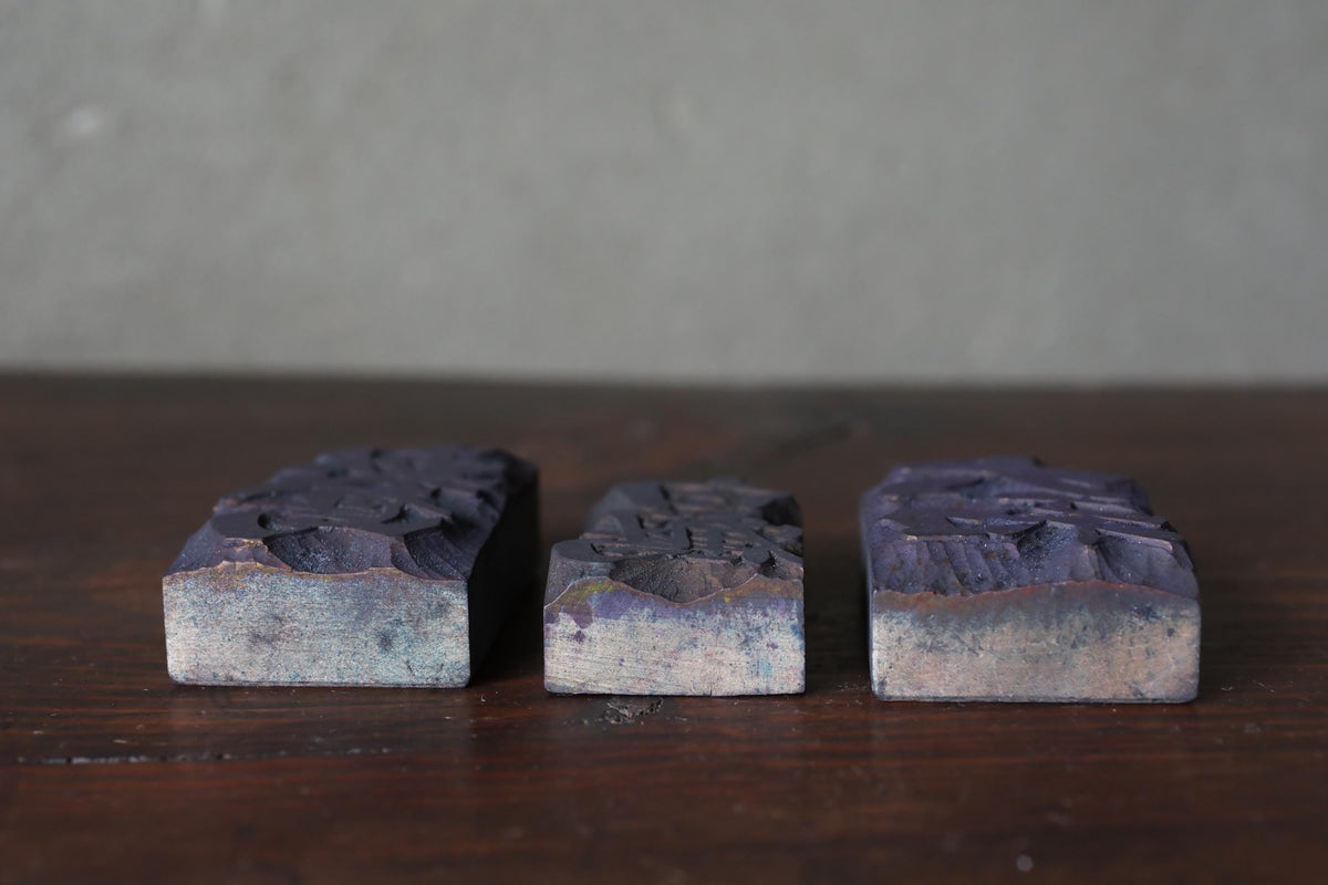 Three rectangular blocks of varying sizes and shapes are arranged on a wooden surface.