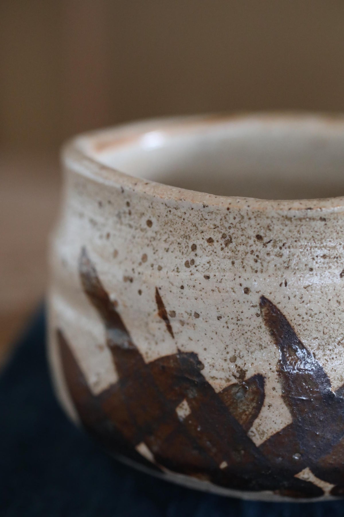 A close-up image of a ceramic bowl with a textured surface and a dark brown pattern on it.