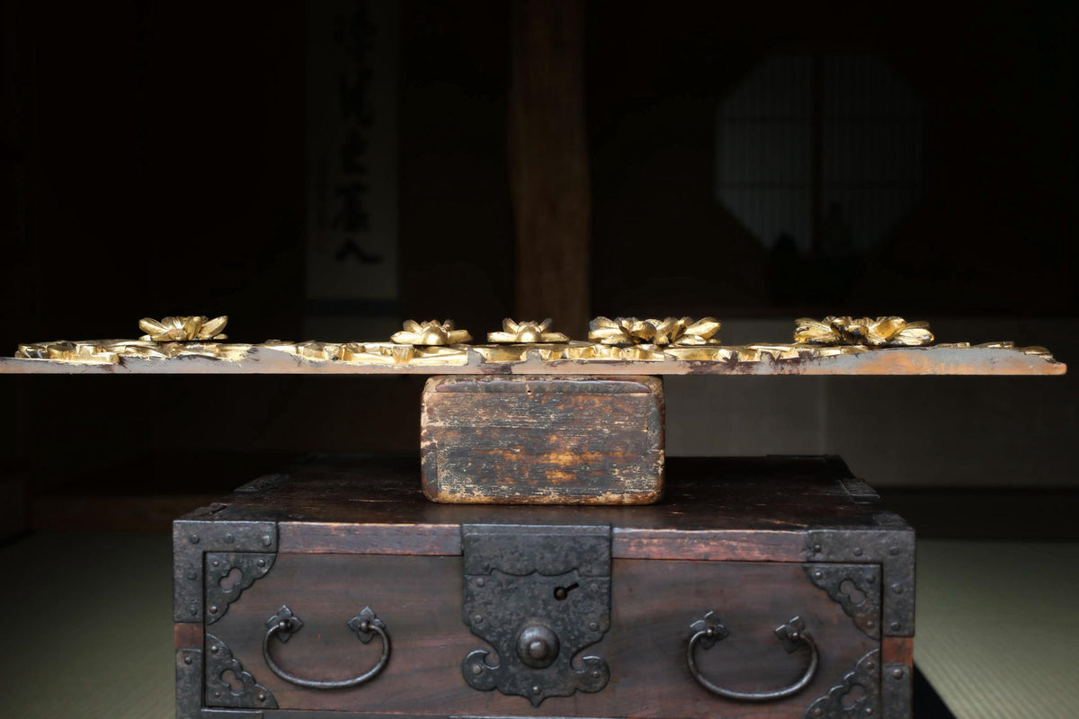a wooden chest with a lid and handles, placed on a wooden table. The chest has a lid with a decorative design and a handle on the front.