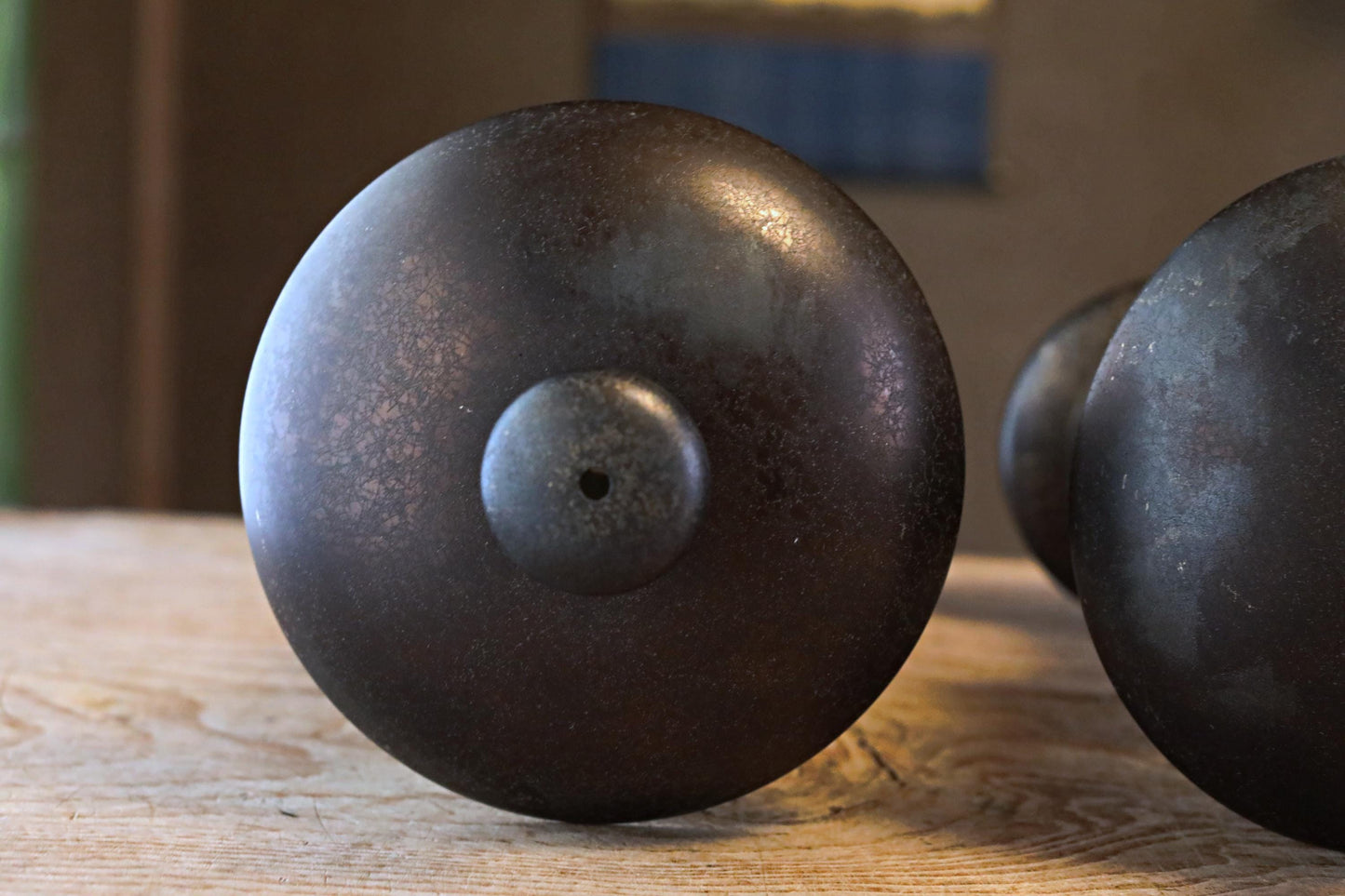 a close-up view of a dark, round metal object with a hole in the center, resting on a wooden surface.