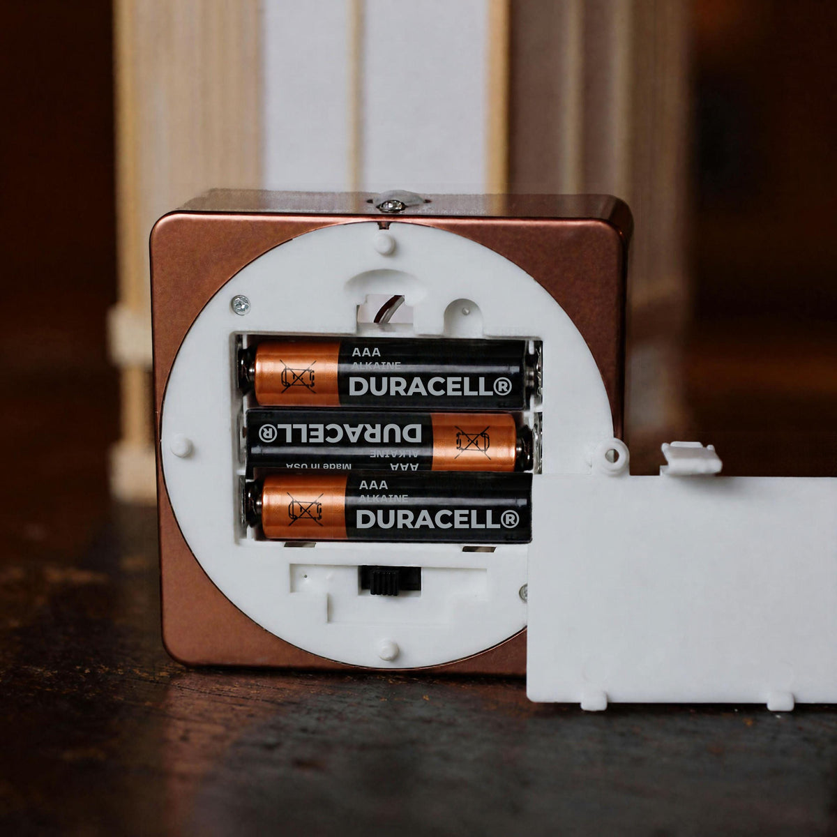 the inside of a Duracell clock, with three AAA Duracell batteries visible inside the clock.