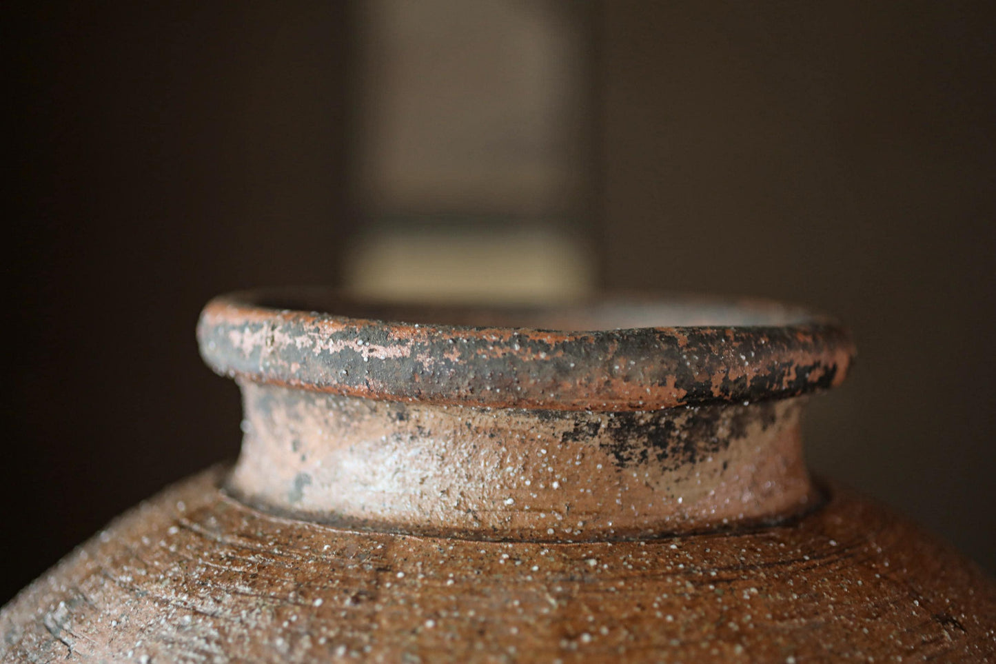 A close-up view of a rusted, weathered clay pot with a textured surface.