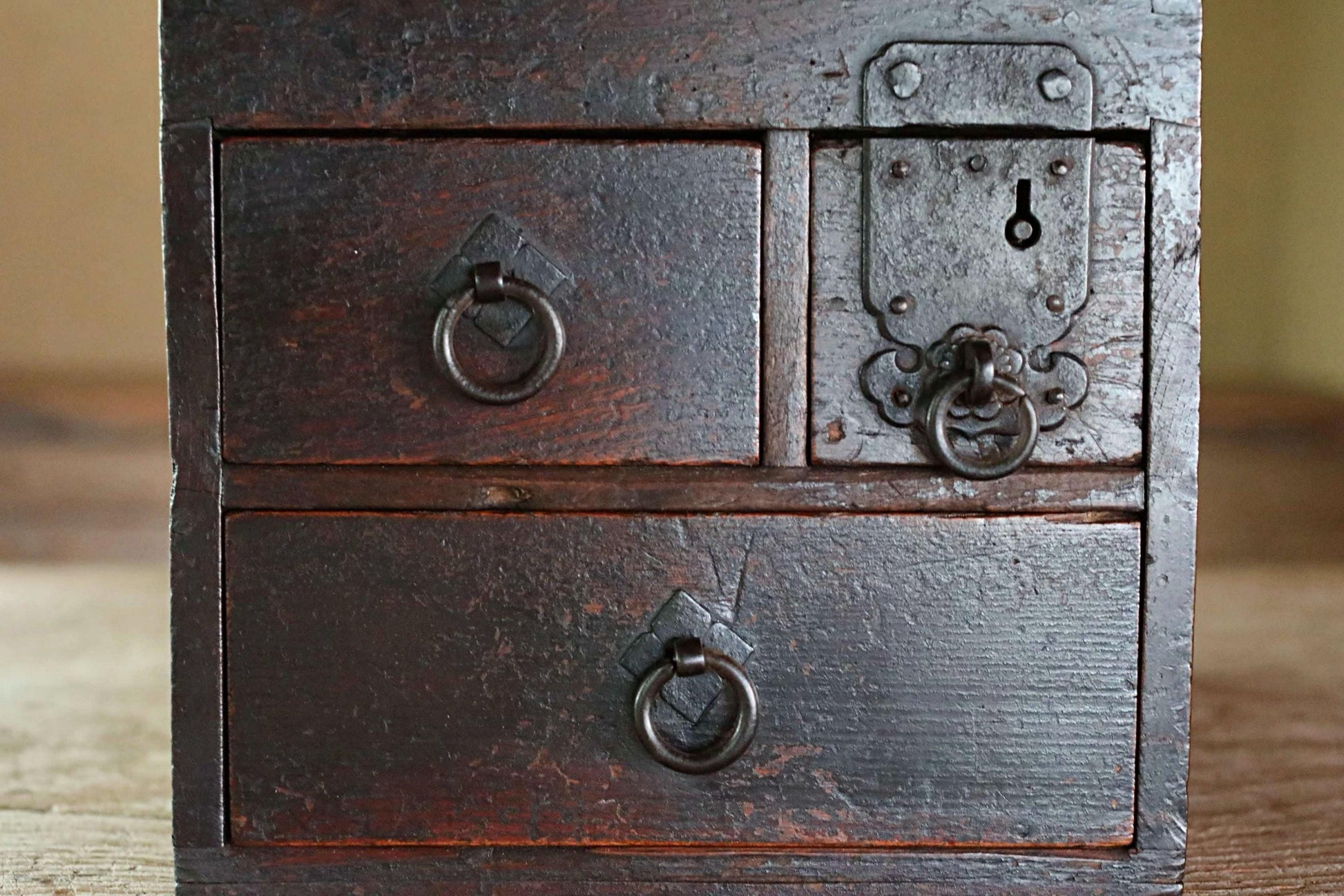 a close-up view of a dark wooden drawer with metal handles and a lock, likely a traditional Japanese drawer or chest.
