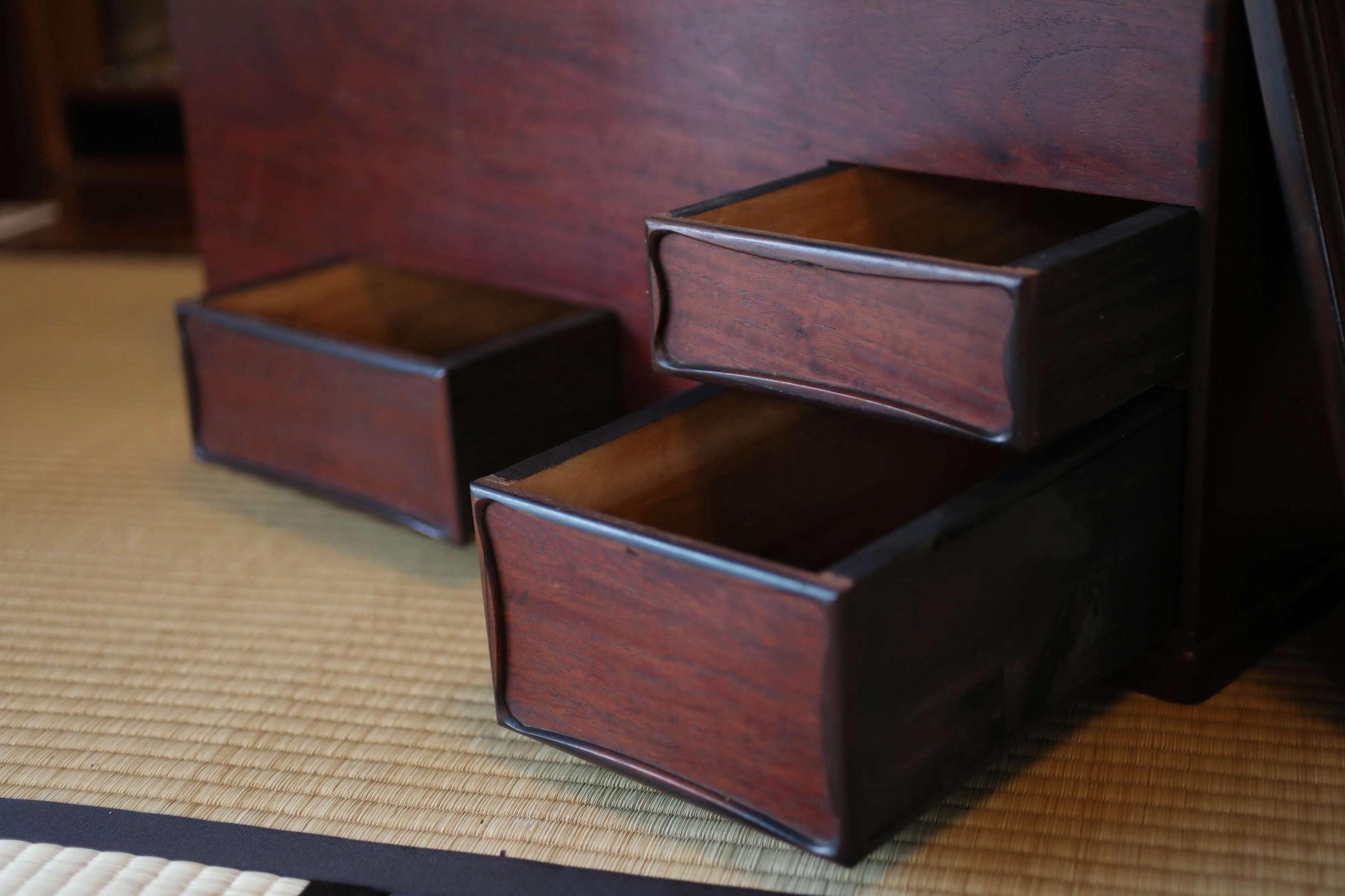 a close-up view of two wooden drawers with empty compartments, placed on a woven mat or mat-like surface.