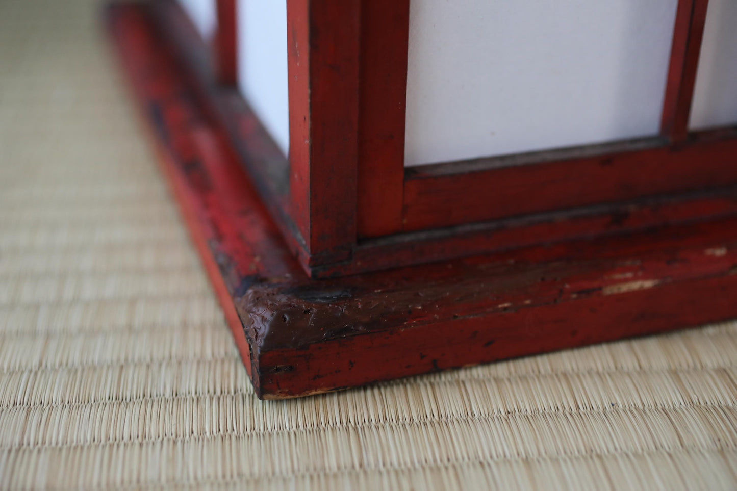 a close-up view of a red wooden frame with a white interior, resting on a woven mat.