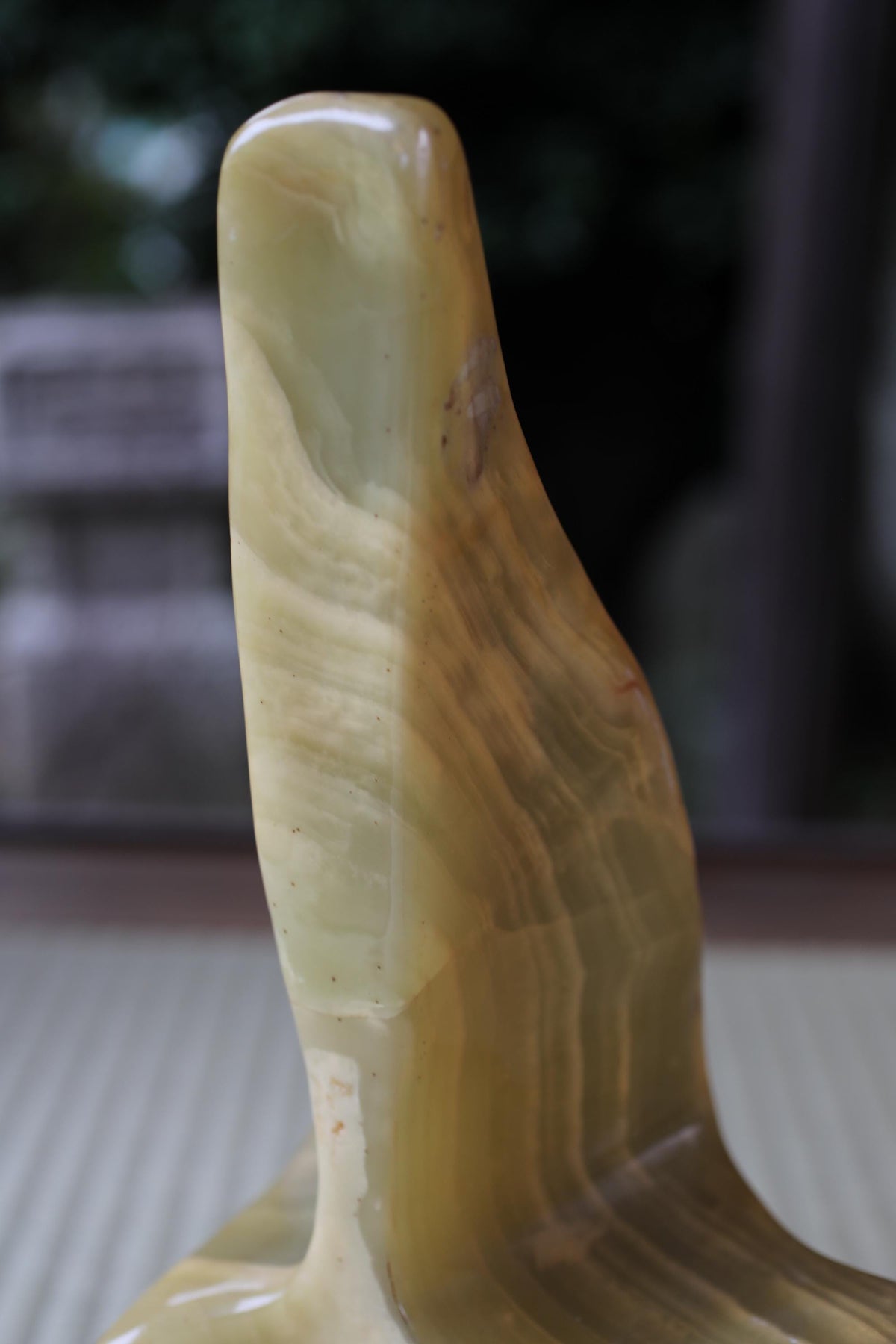 A close-up image of a curved, textured object with a yellowish-green hue, possibly a piece of pottery or a sculpture.