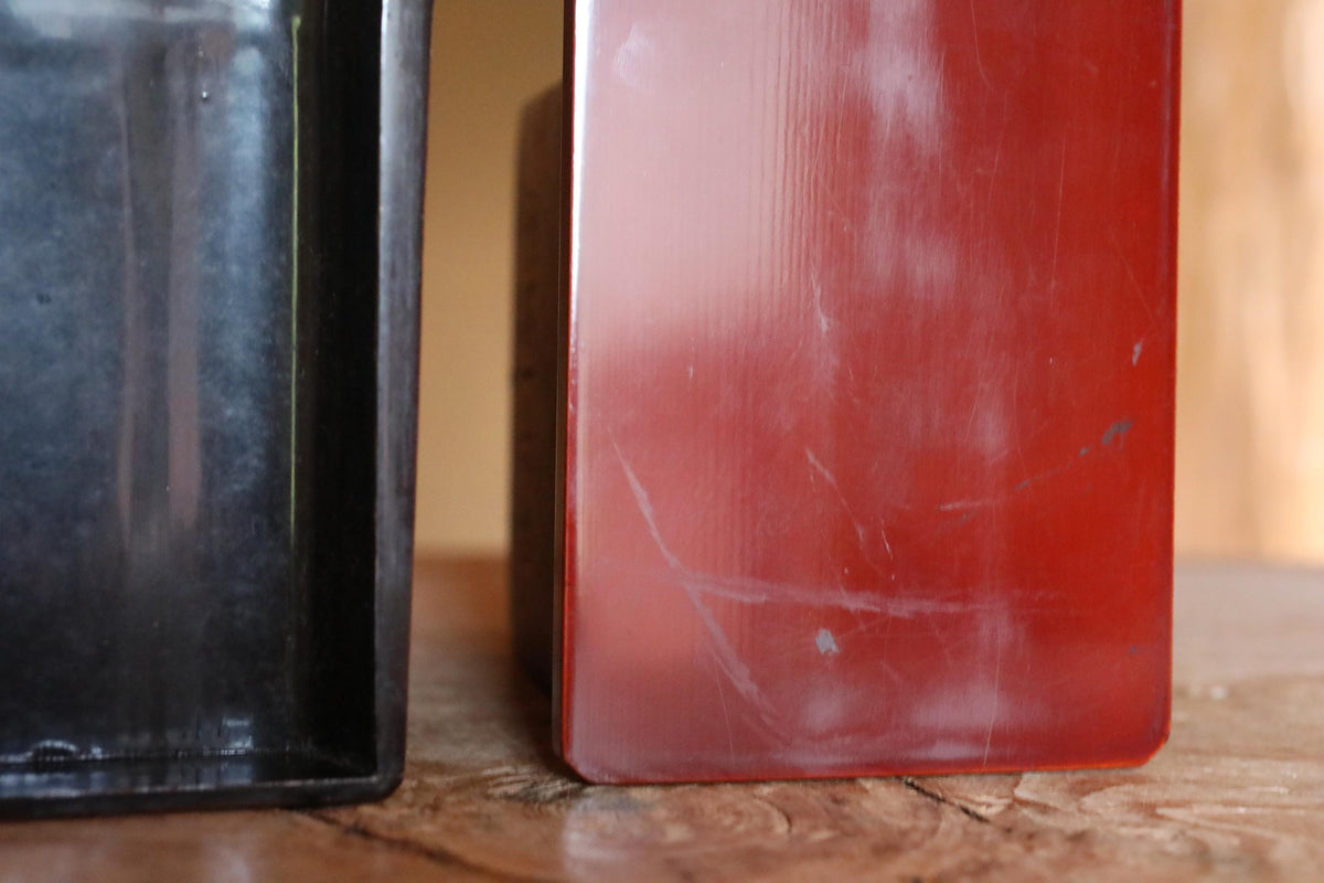 a close-up of two objects, one red and one black, placed on a wooden surface.