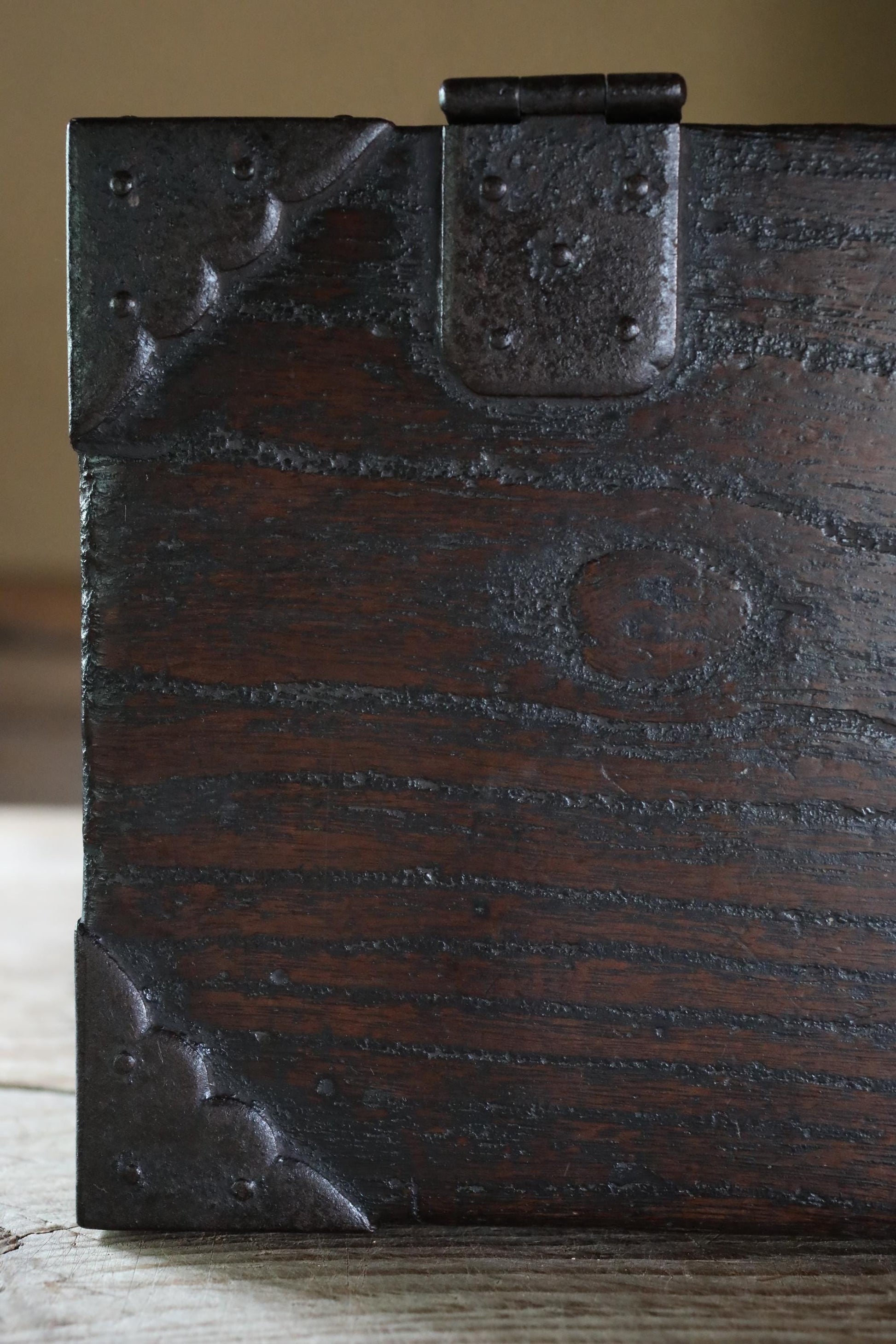 a close-up view of a dark wooden surface with a metal latch and a decorative metal design on the corner.
