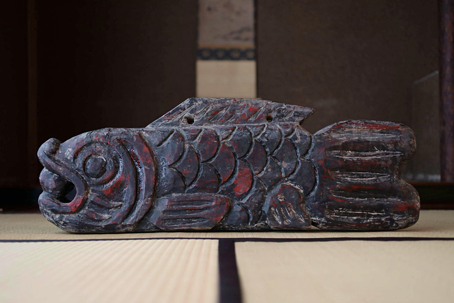 a large, intricately carved wooden fish sculpture with a dark red and black color scheme.
