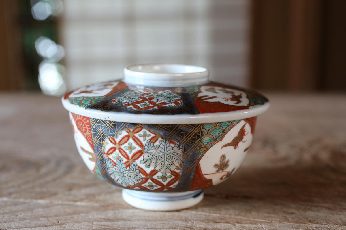 A colorful ceramic bowl with intricate patterns and designs, placed on a wooden surface.