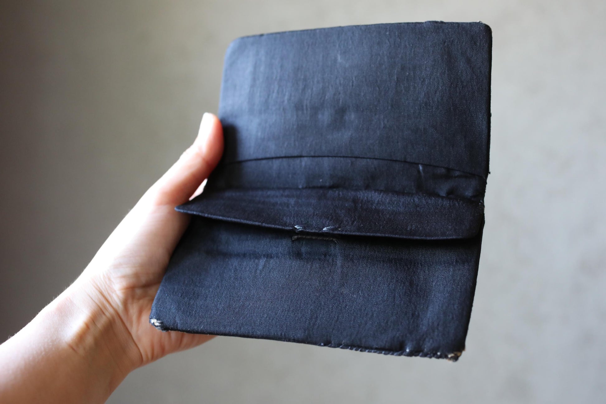 A hand holding a black wallet or card case.