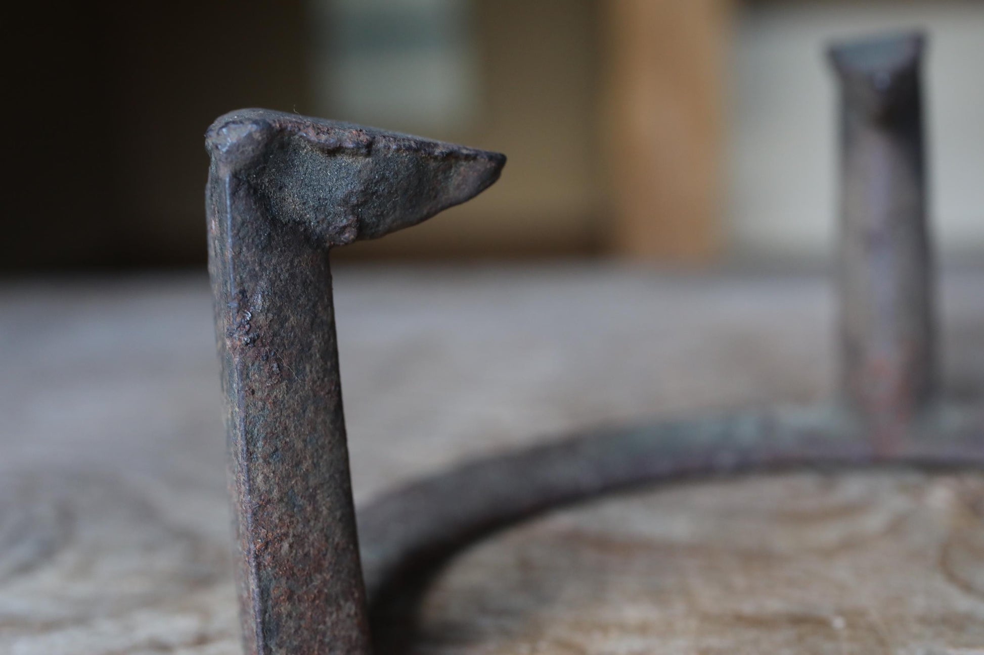 a close-up view of a rusted metal object, possibly a piece of furniture or a tool, with a blurred background.