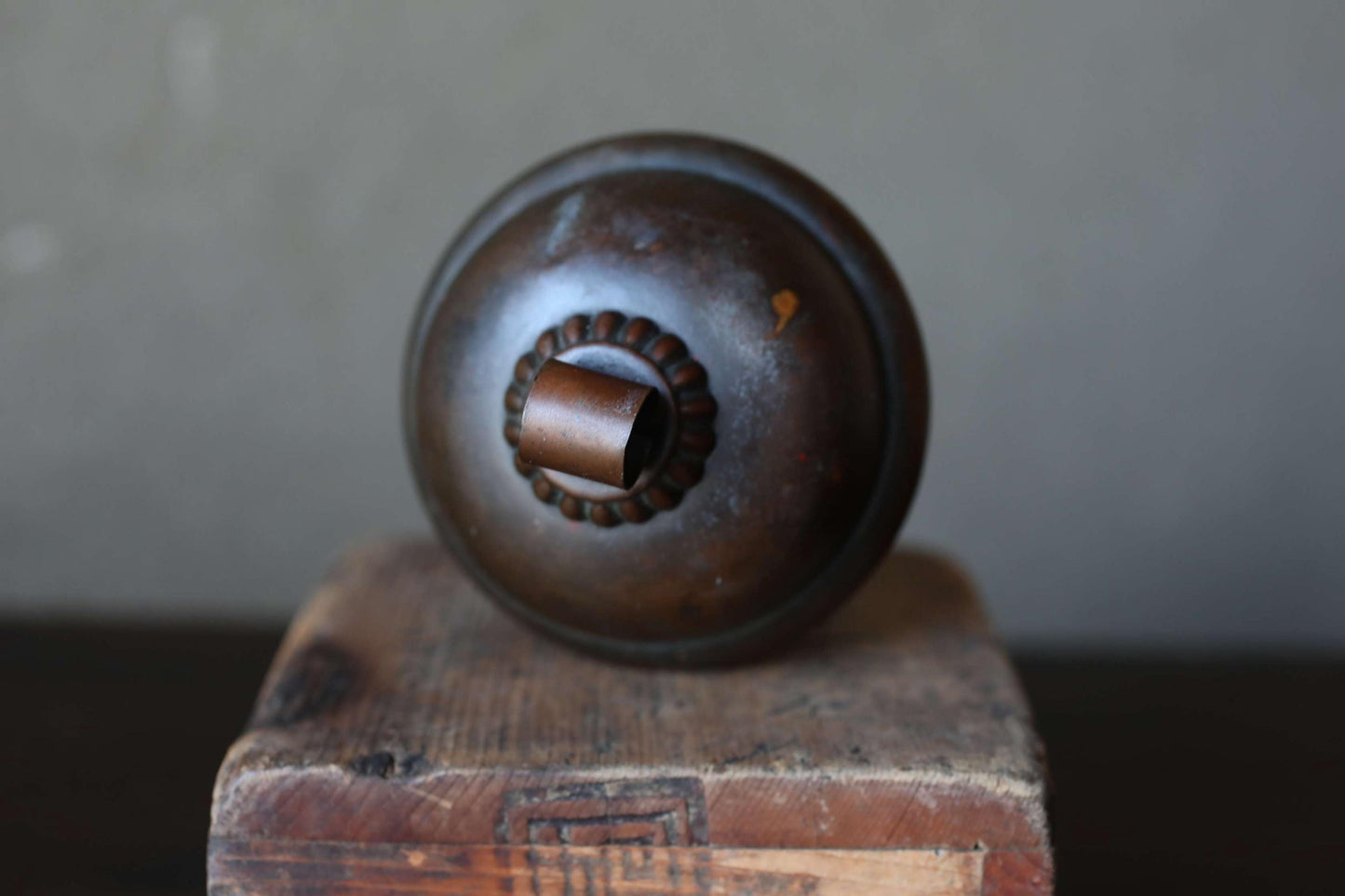 A round, dark-colored metal object with a small, circular opening on top, sitting on a wooden surface.