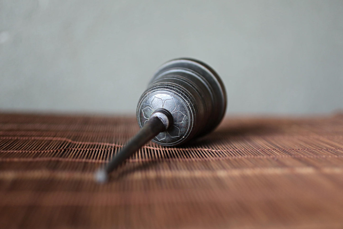A metal object with a circular design on its surface is lying on a wooden surface.