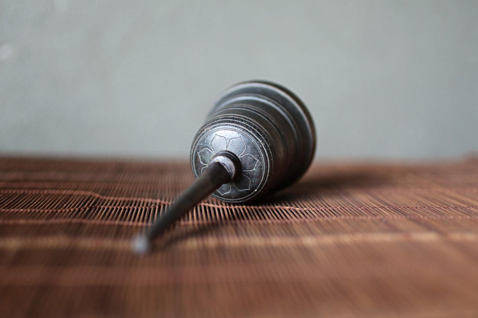 A metal object with a circular design on its surface is lying on a wooden surface.
