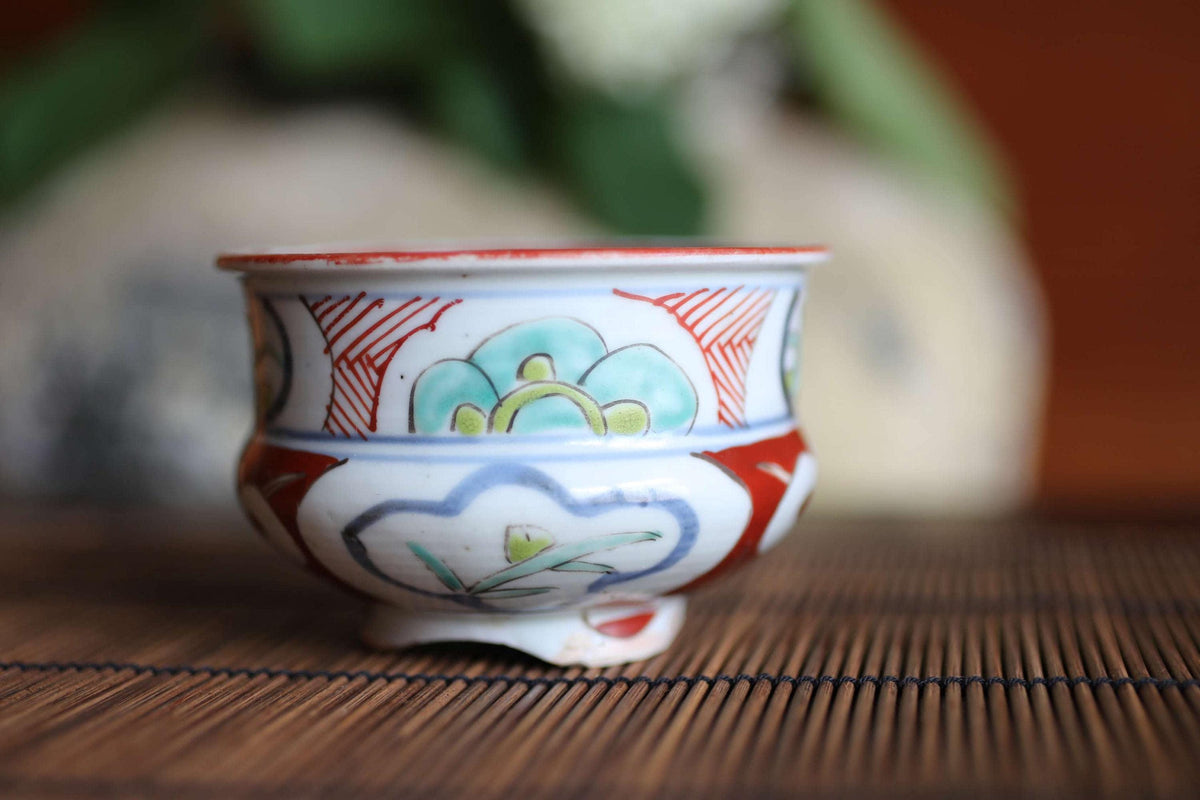 A colorful ceramic bowl with a floral design sits on a bamboo mat.