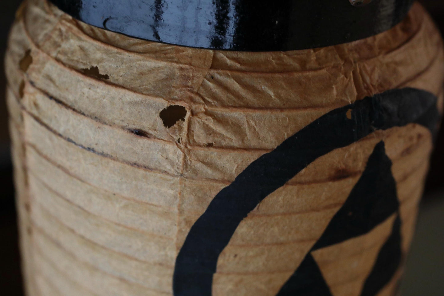 A close-up view of a beige paper lantern with a black symbol or logo on it.