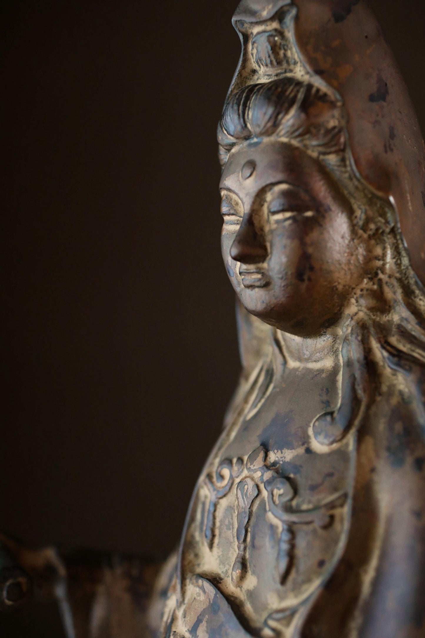 A close-up view of a bronze statue depicting a serene, contemplative figure with intricate details and a pensive expression.