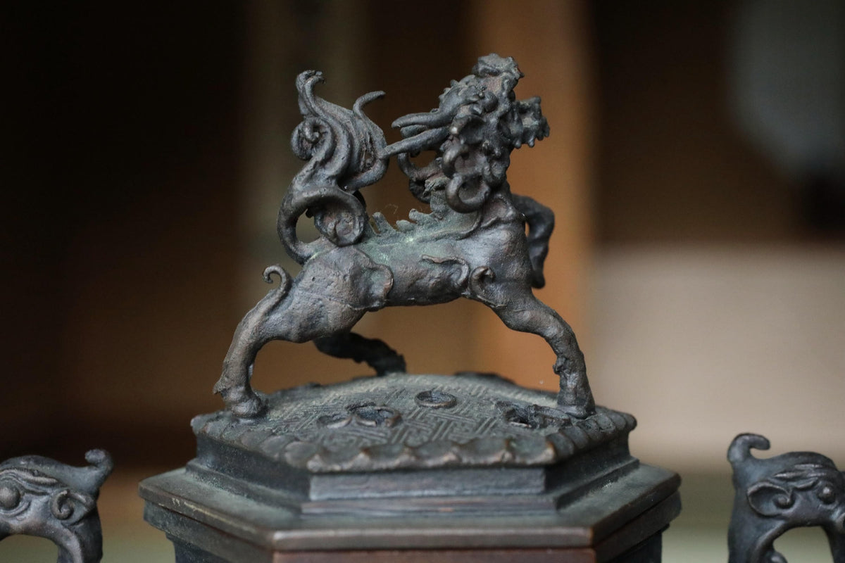 A bronze statue of a lion with a flowing mane and tail, standing on a pedestal with intricate designs.
