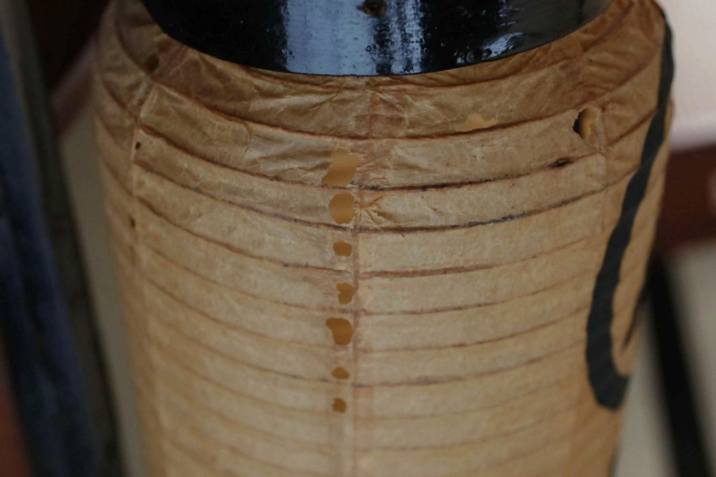 A close-up view of a brown paper lantern with a black top, featuring a series of small holes or punctures along its surface.