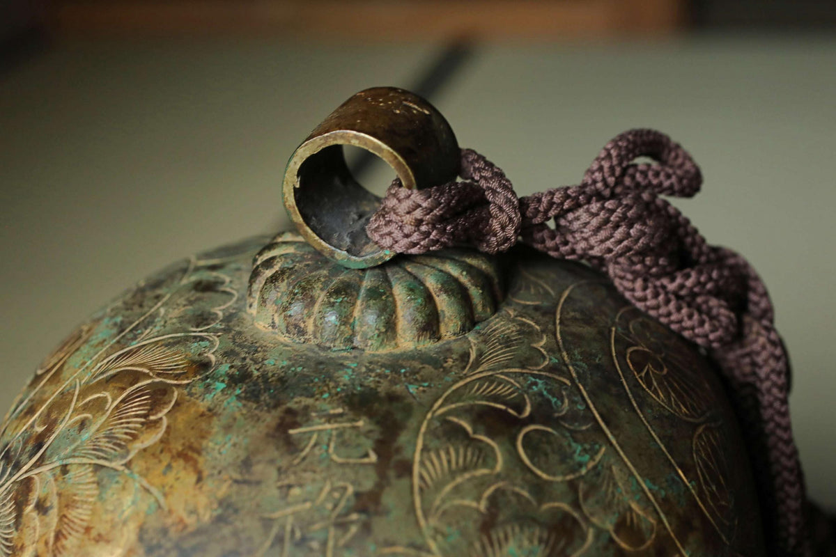a close-up view of a decorative metal bell or vase with intricate patterns and designs.