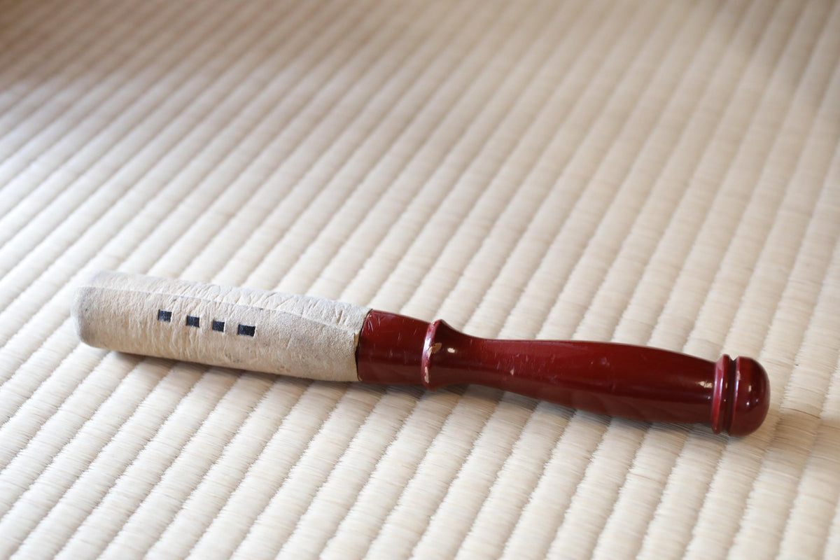 A red-handled object with a white cord wrapped around it, resting on a white surface.