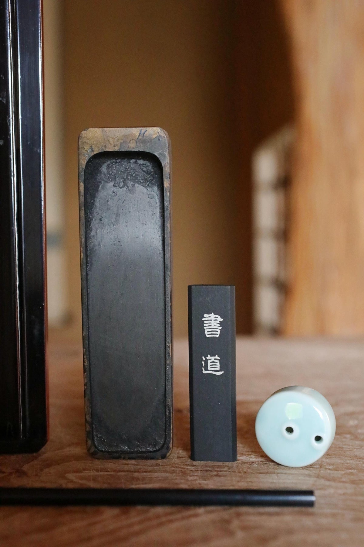 a black rectangular object, a black rectangular object with Chinese characters, and a small white object on a wooden surface.