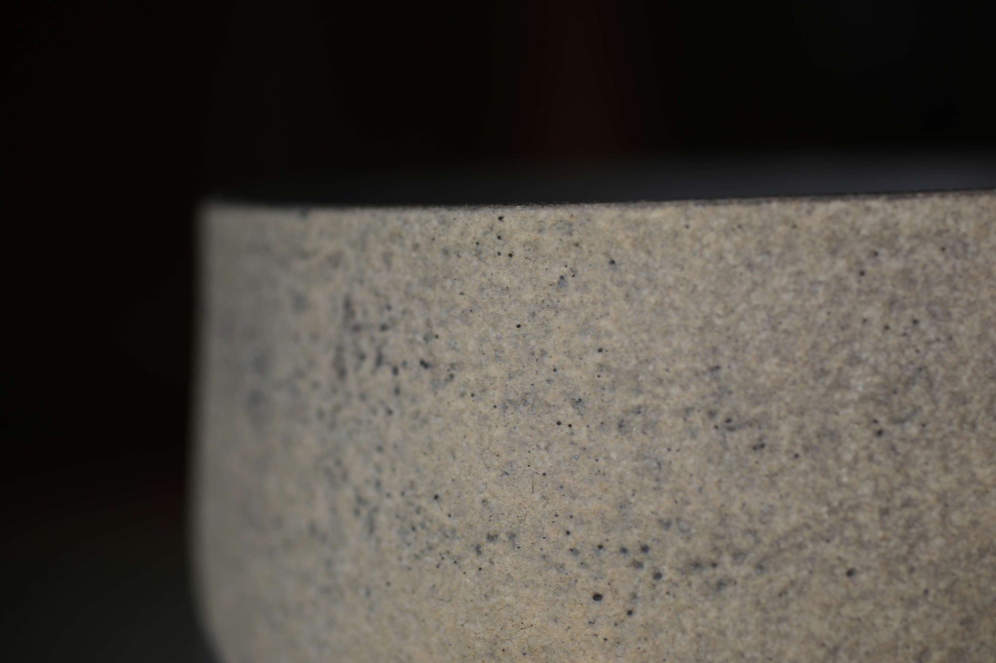 A close-up view of a textured, speckled surface, possibly a piece of pottery or a ceramic object.