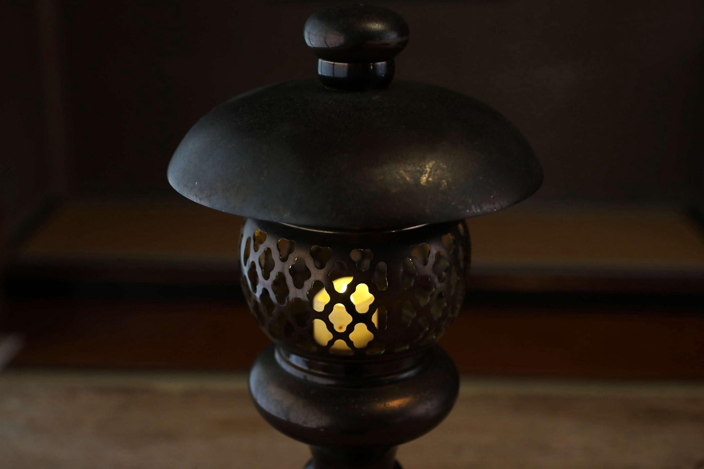 A black lantern with a lit candle inside, casting a warm glow in the dimly lit room.