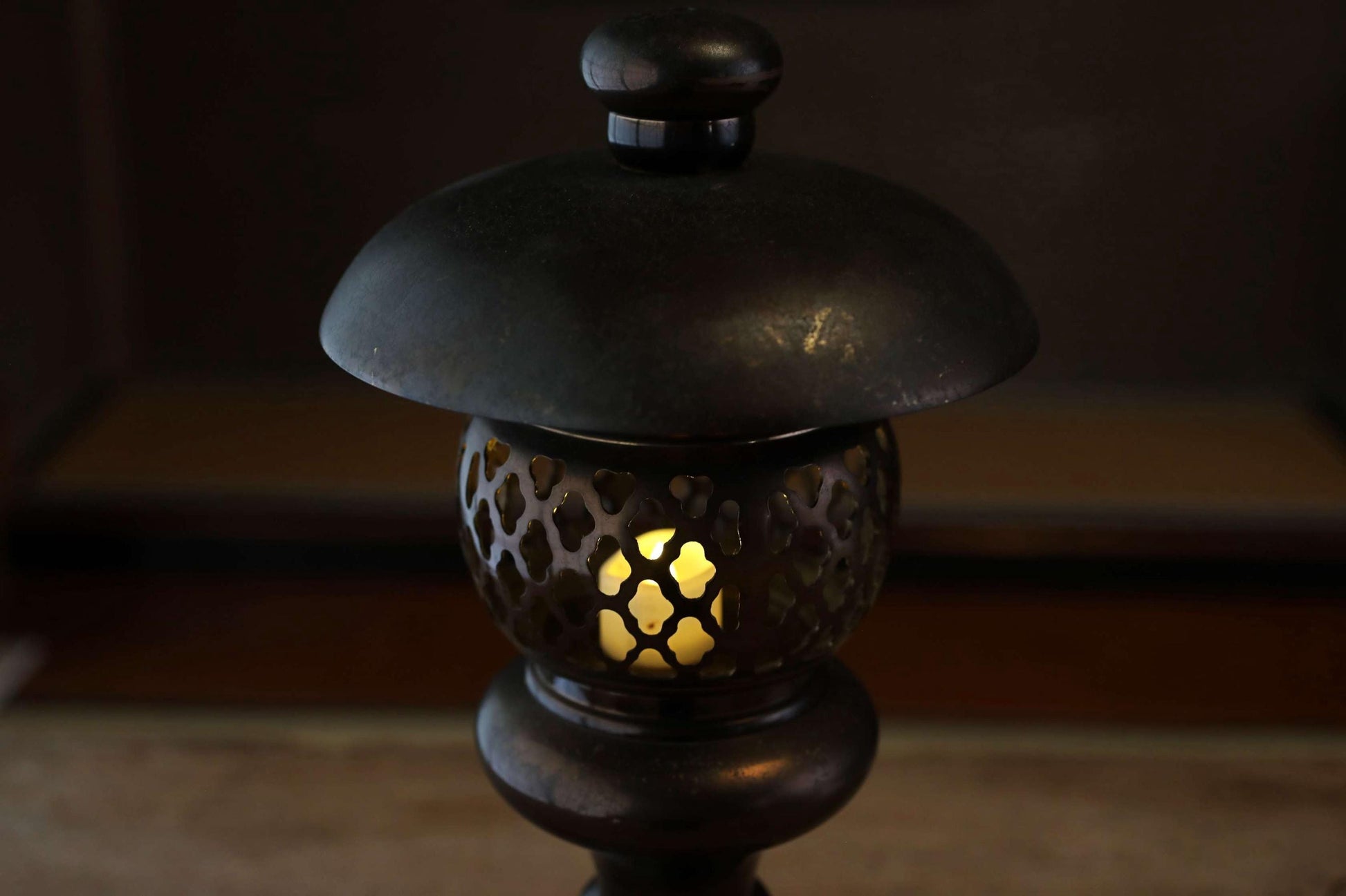 A black lantern with a lit candle inside, casting a warm glow in the dimly lit room.