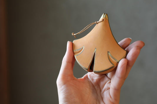 A hand holding a small, orange-colored ceramic object with a pointed end.