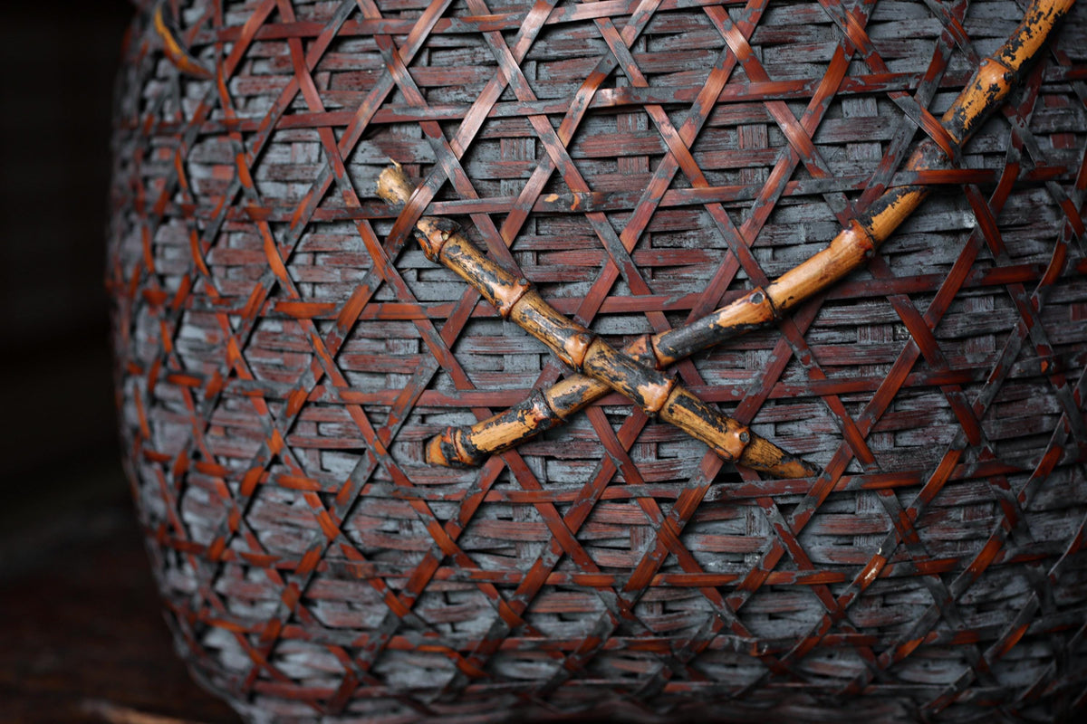 A close-up view of a woven basket with a dark brown color and a pattern of red and brown woven lines.