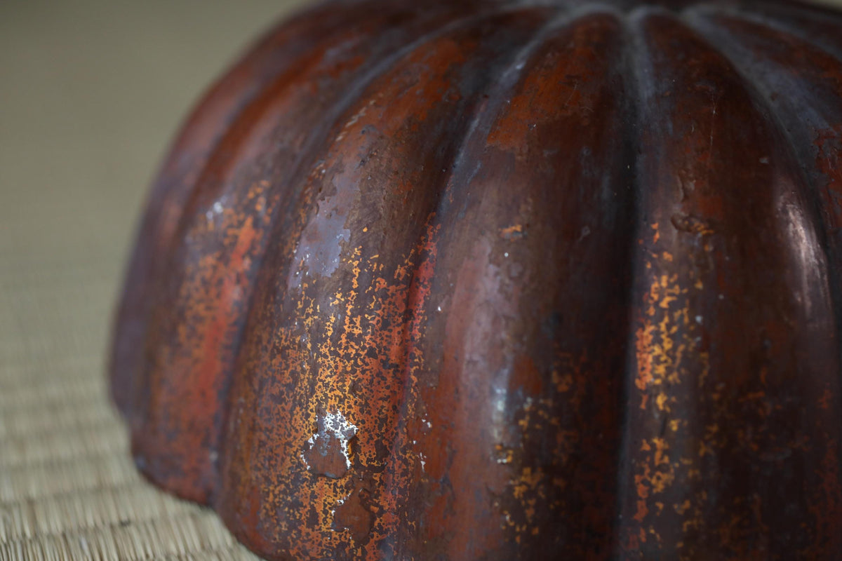 A close-up image of a rusted, antique-looking metal object with a textured, weathered appearance.