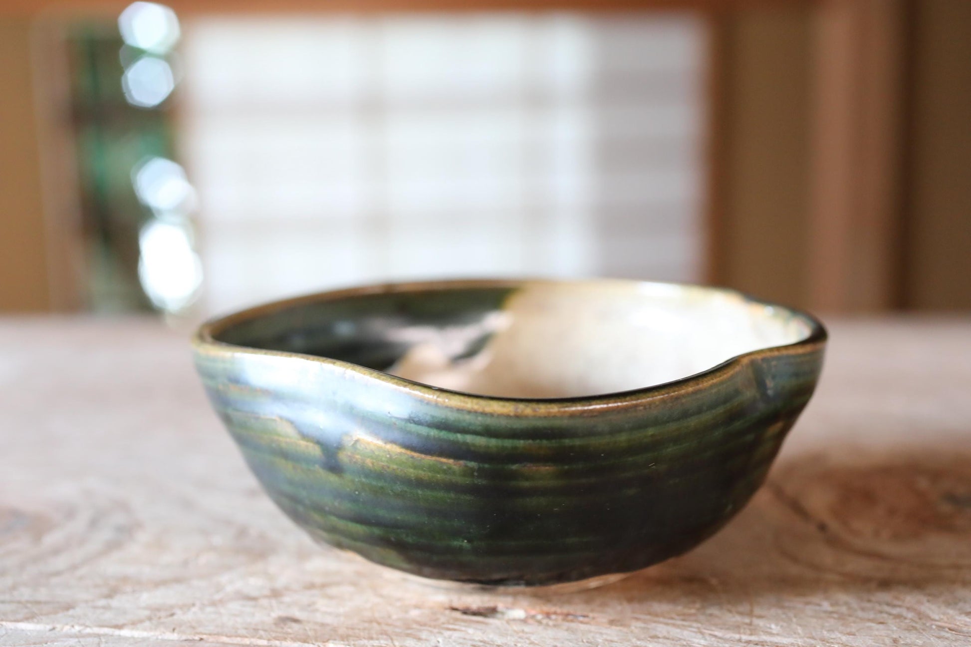 A ceramic bowl with a green and white pattern sits on a wooden surface.