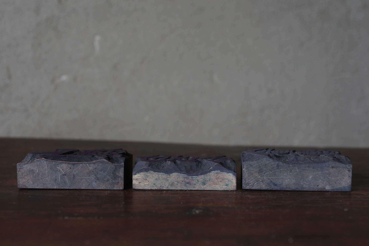 Three rectangular blocks of varying sizes are arranged on a wooden surface against a plain gray wall.