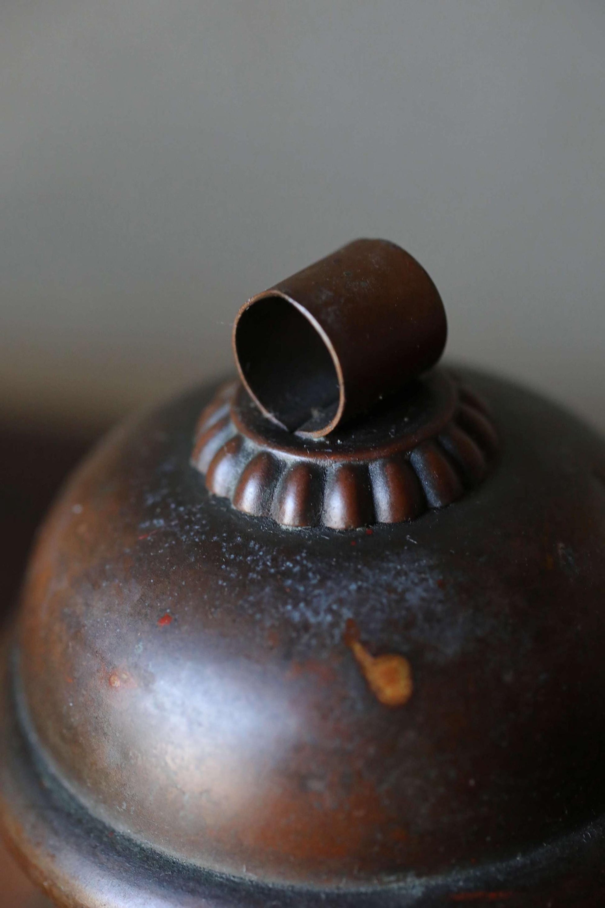 A close-up image of a dark, textured metal object with a small, circular hole in the center.